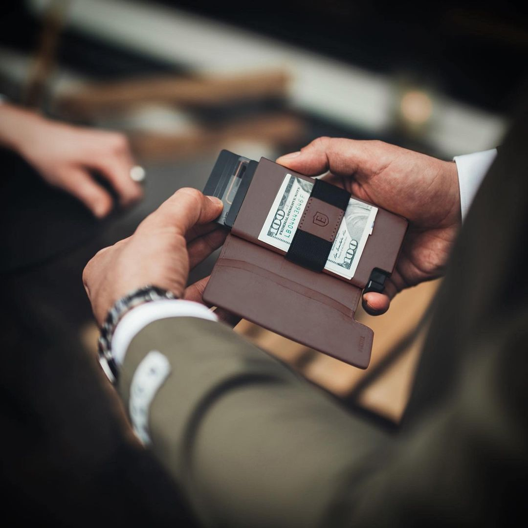 Man taking card out of ester wallet, with cash visible