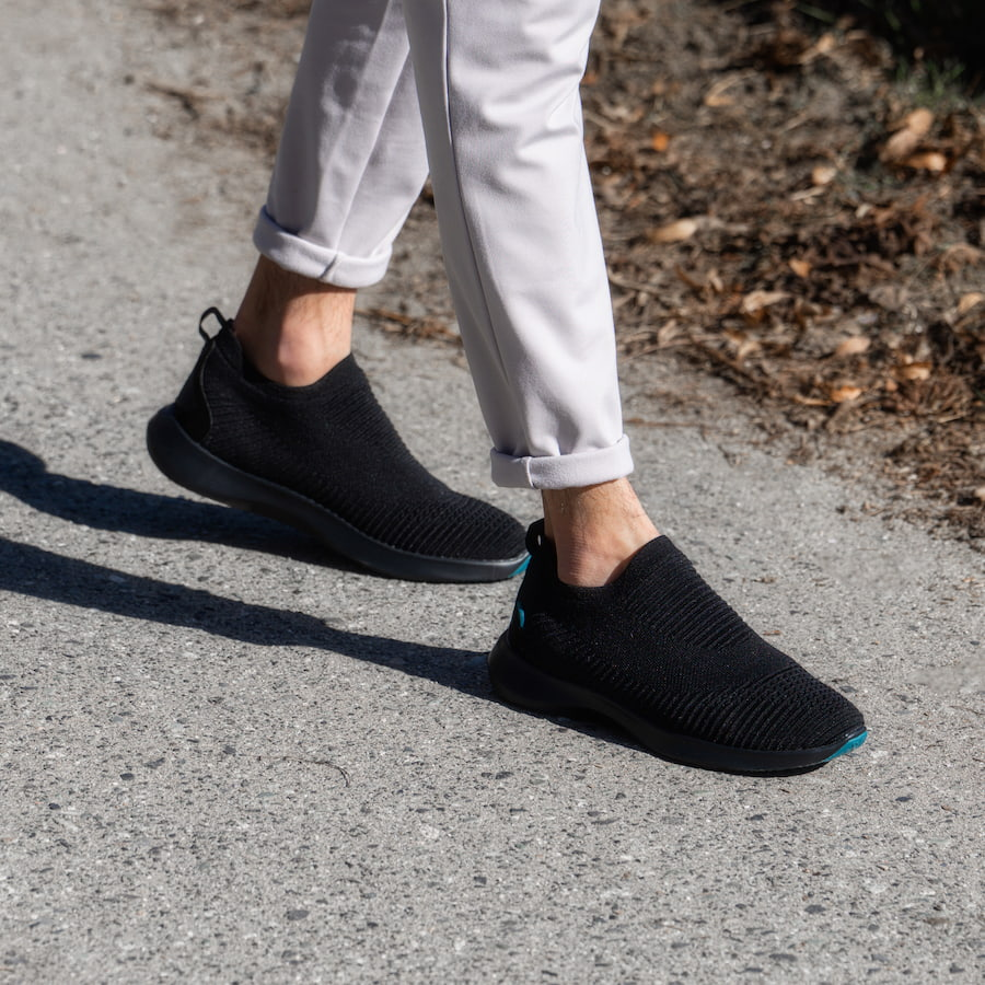 man walking outside with black vessi shoes