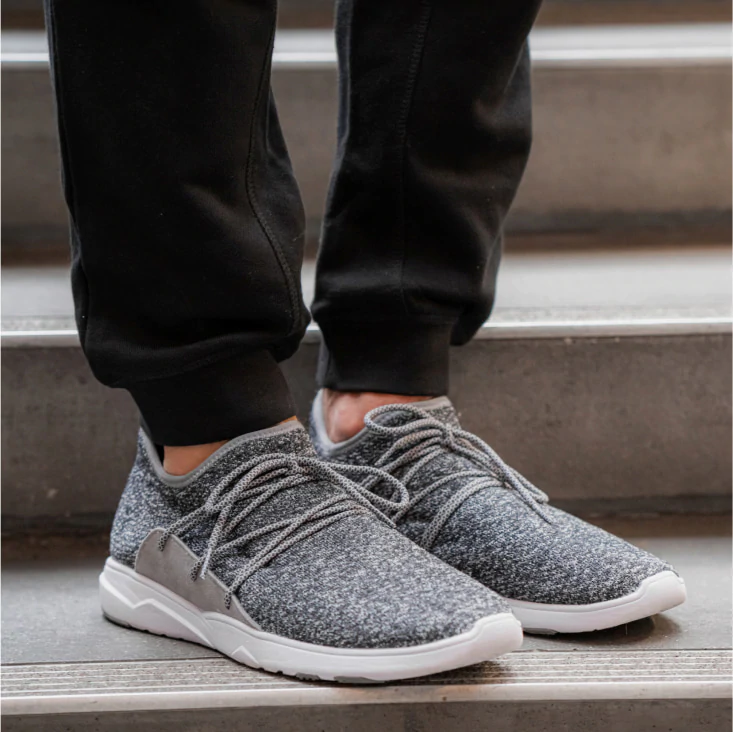 man with black pants standing on stairs with vessi shoes