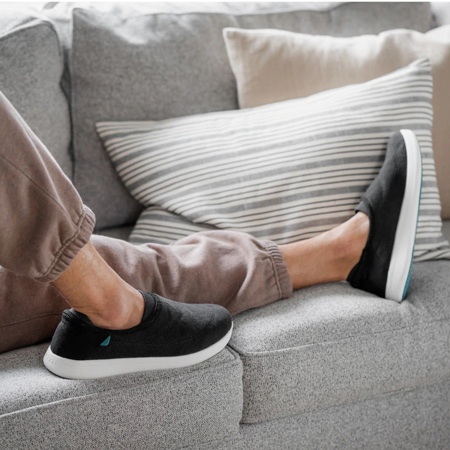person laying on couch wearing vessi sunday slippers