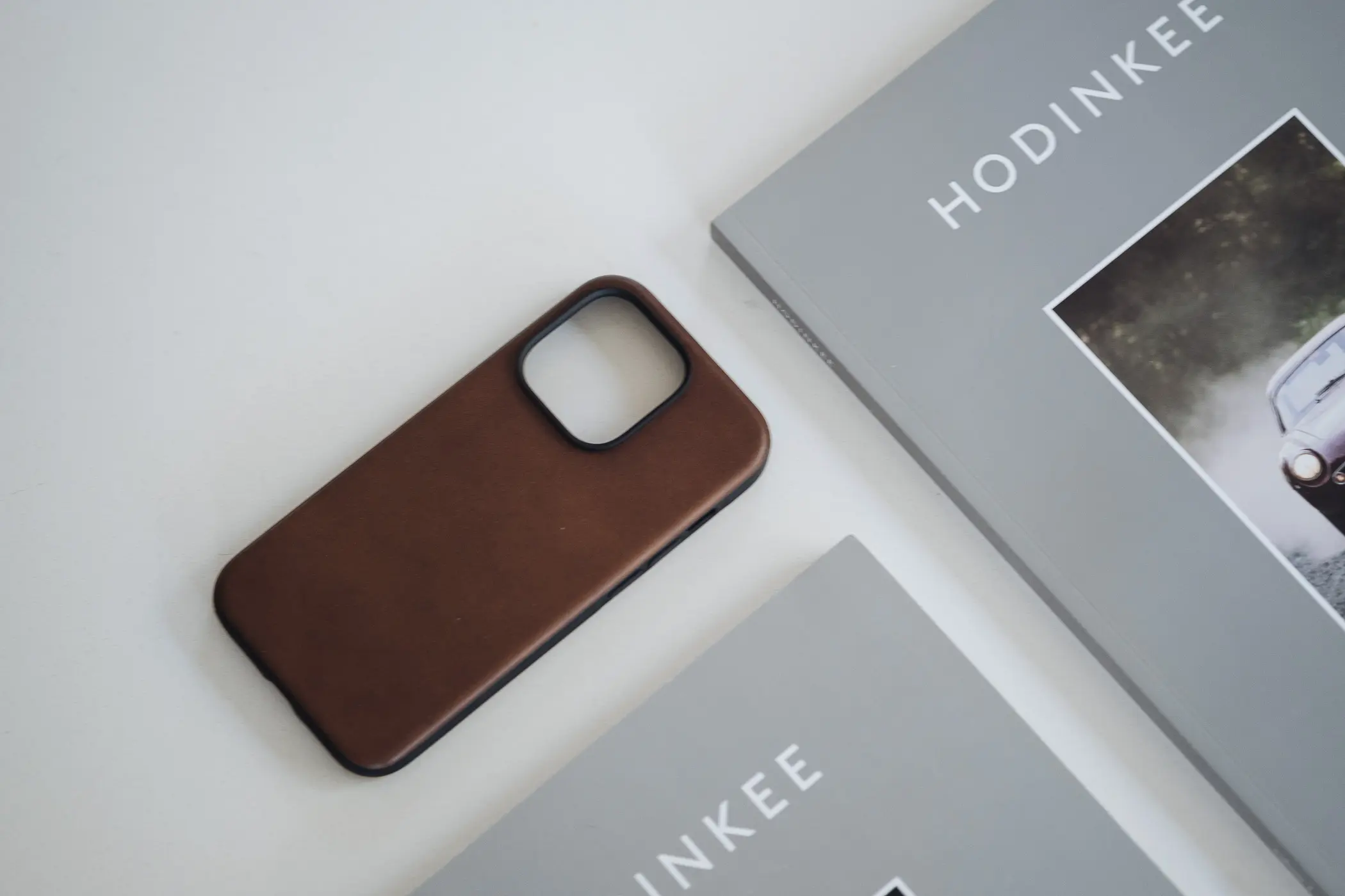 Leather iphone case on white table beside books