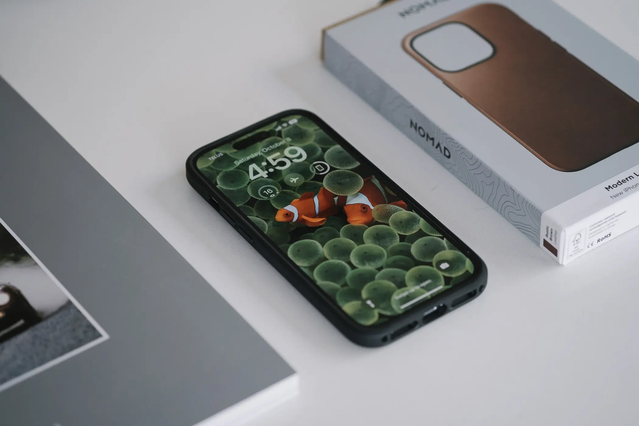 iphone beside magazine and case box on white table