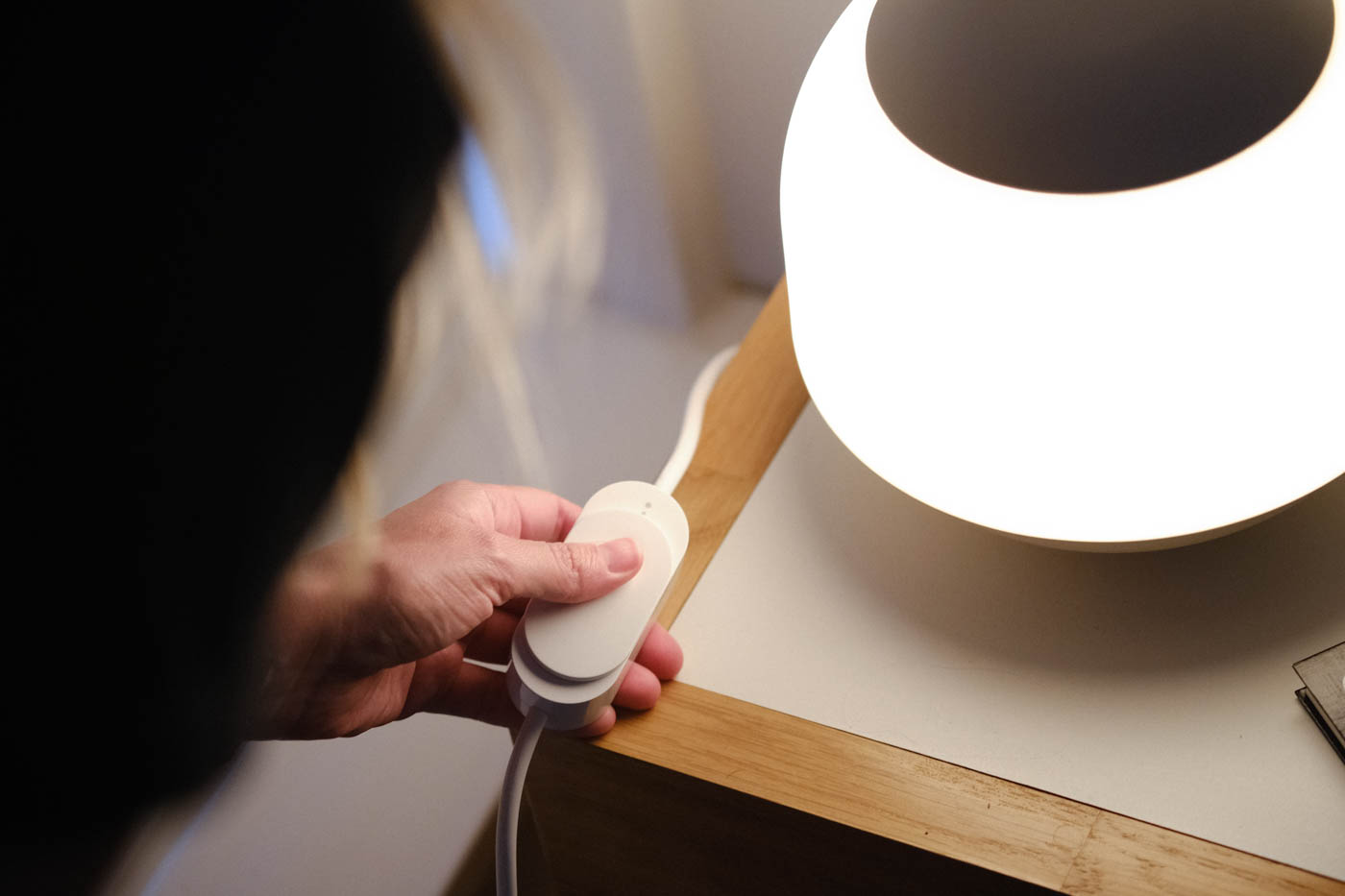 Woman adjusting dimmable switch on light on nightstand